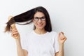 a joyful sweet woman, brunette, with glasses, combs her hair with a wooden massage comb and smiling looks at the camera