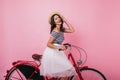 Joyful tanned girl sitting on red bicycle in studio. Indoor portrait of ethusiastic female model in Royalty Free Stock Photo