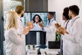 Joyful team of multiracial doctors during online video meeting indoors, clapping hands after successful presentation of