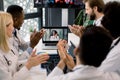 Joyful team of multiracial doctors during online video meeting indoors, clapping hands after successful speech of their