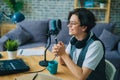 Joyful teen speaking in microphone in studio recording podcast alone