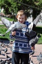 The joyful teenage boy feeds pigeons from hands Royalty Free Stock Photo