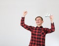 Joyful teenage boy playing video games isolated over white background celebrating success raising hands up while holding the Royalty Free Stock Photo