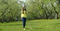 Joyful teenager girl is strolling alone in park area and laughing, frontal view