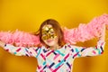 A joyful teenager girl wearing a colorful Brazil carnival mask