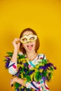 A joyful teenager girl wearing a colorful Brazil carnival mask