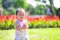 Joyful Toddler Clapping Hands in Flower Garden. Delighted baby boy claps his hands while standing in lush garden. Royalty Free Stock Photo