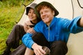 Joyful tourist couple taking selfie while sitting at camping tent in green forest Royalty Free Stock Photo