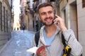 Joyful tourist holding map or dictionary during a vacation and calling by phone