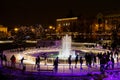 Joyful tourists ice skate around a fountain in a Christmas park in Zagreb.