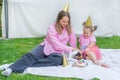Joyful two girls sisters celebrating their dog\'s birthday with tasty cake in the garden.