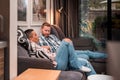 Joyful two persons couple comfortably sitting on sofa at home communicating, talking, sharing feelings, supporting each other. Royalty Free Stock Photo