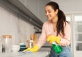 Joyful woman cleaning countertop with spray and cloth Royalty Free Stock Photo