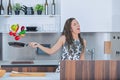 Joyful woman cooking, colorful flying vegetables, singing Royalty Free Stock Photo