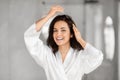 Smiling woman in a white robe playing with hair