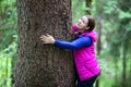 Joyful woman embracing pine stem