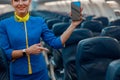 Smiling stewardess with mobile phone standing in airplane cabin Royalty Free Stock Photo