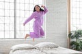 Joyful woman jumping on bed at home