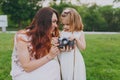 Joyful woman in light dress and little cute child baby girl take picture on retro vintage photo camera in park. Mother Royalty Free Stock Photo