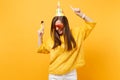 Joyful woman in orange funny glasses birthday party hat with playing pipe rising hands pointing index fingers up