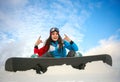 Joyful woman snowboarder sitting on top of mountain on blue sky Royalty Free Stock Photo