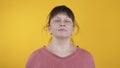 Joyful woman takes off a medical mask on a yellow background