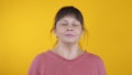 Joyful woman takes off a medical mask on a yellow background