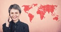 Joyful woman talking on phone abroad, smiling over pink wall with world map. Trendy positive tourist girl speak on smartphone in