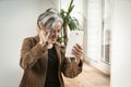 Joyful woman waves her hand using tablet computer for communication with loved ones in internet. Happy aged woman have Royalty Free Stock Photo