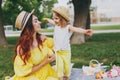 Joyful woman in yellow clothes play in park, have fun and hug with little cute child baby girl hold soap bubble blower Royalty Free Stock Photo