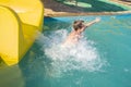 happy child slides down the yellow water slide in the water park. Royalty Free Stock Photo