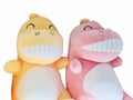 A joyful yellow and pink dinosaur doll smiles wide with split teeth on a white background