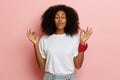 Joyful yoga meditating woman, standing isolated over pink wall, she shows okay sign with both hands up