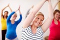 Joyful yoga. A multi-ethnic group of pregnant women doing exercises with their arms stretched upwards.