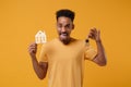 Joyful young african american guy in casual t-shirt posing isolated on yellow orange background, studio portrait. People