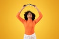 Joyful young woman with curly afro hair in an orange turtleneck and white pants Royalty Free Stock Photo