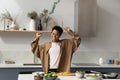 Joyful young African American woman dancing, cooking in kitchen. Royalty Free Stock Photo