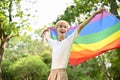 Joyful young Asian gay man with an LGBT rainbow flag, feeling freedom and proud