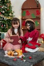 A joyful young Asian girl is reading a Christmas fairy tale story in a book to her younger sister Royalty Free Stock Photo