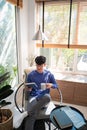 Joyful young Asian man in casual clothes and eyeglasses reading book while relaxing at living room of his home Royalty Free Stock Photo