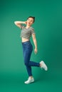 Joyful young Asian woman standing on one leg. Full length view of blissful girl dancing on green background