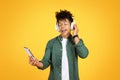 Joyful young black guy listening to music on yellow background Royalty Free Stock Photo