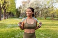 Joyful young black woman in sports clothes posing with jumping rope at park. Active lifestyle concept Royalty Free Stock Photo