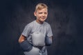 Joyful young boy boxer with blonde hair dressed in a white t-shirt with boxing gloves posing in a studio. Isolated on a Royalty Free Stock Photo