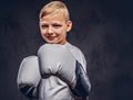 Joyful young boy boxer with blonde hair dressed in a white t-shirt with boxing gloves posing in a studio. Isolated on a Royalty Free Stock Photo