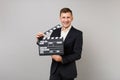 Joyful young business man in classic black suit, shirt holding classic black film making clapperboard isolated on grey Royalty Free Stock Photo