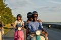 Joyful young couple of diverse friends in helmets smiling at camera while riding a retro scooter and having fun outside Royalty Free Stock Photo