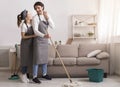 Joyful young couple doing spring-cleaning together, mopping floor and hugging Royalty Free Stock Photo