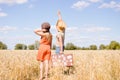 Joyful young couple having fun in wheat field. Excited man and woman pointing at blue sky outdoor Royalty Free Stock Photo