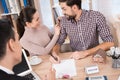 Joyful young couple signs contract for purchase of new house in office of real estate agency. Royalty Free Stock Photo